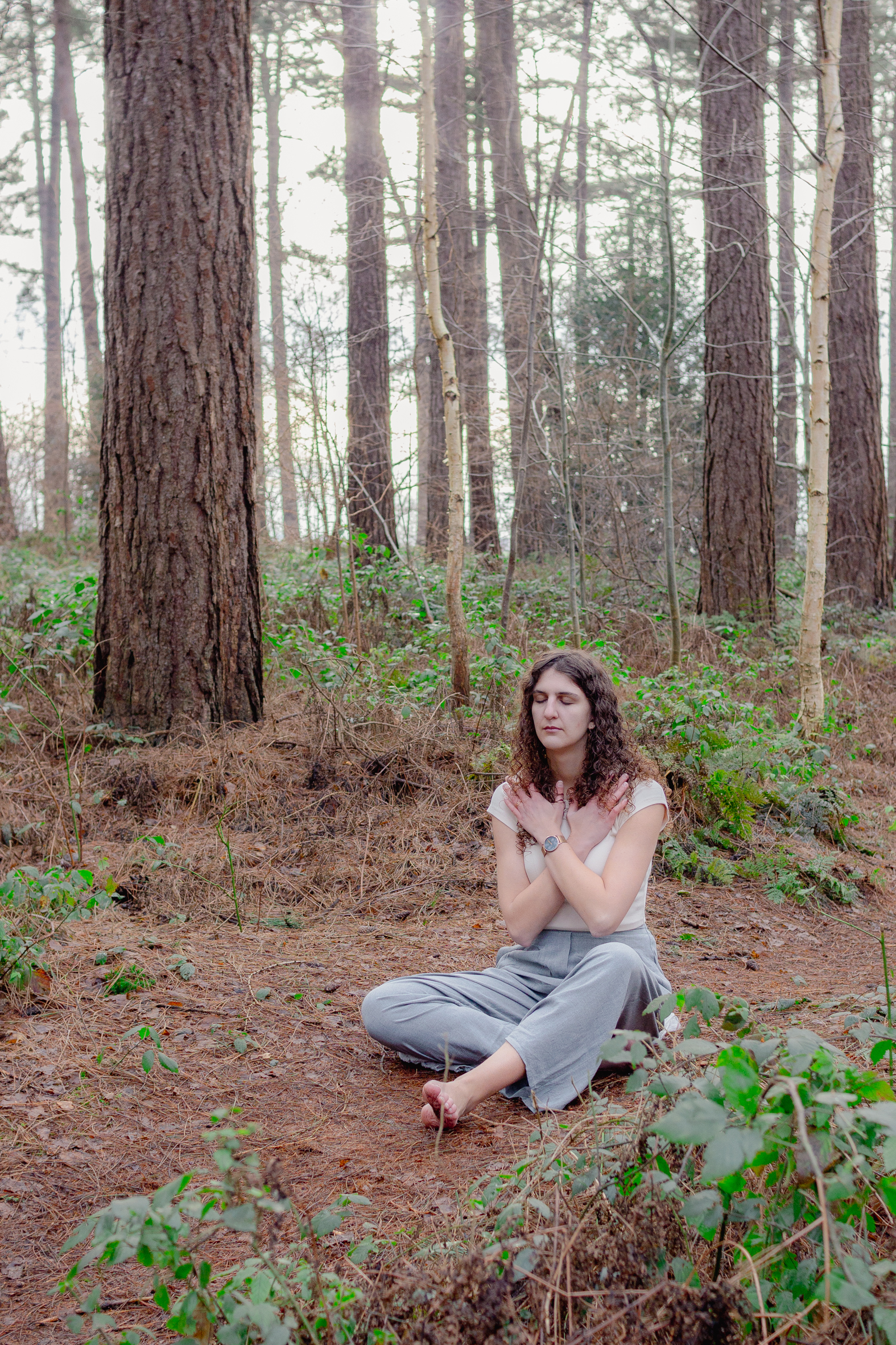Een zittende foto van mezelf terwijl ik een groundingsoefening aan het doen ben. Ik zit in een bos.